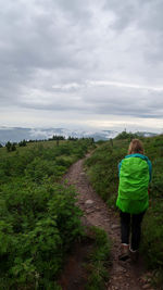 Rear view of woman walking on footpath against sky