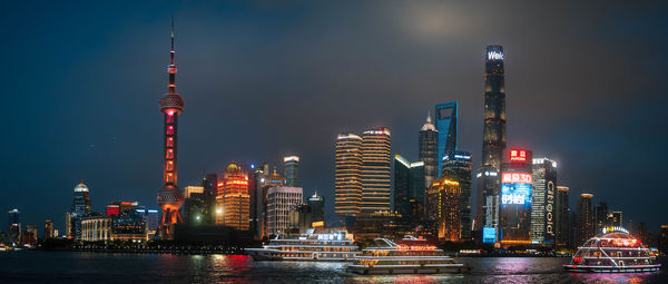 Illuminated buildings in city against sky at night
