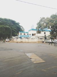 Empty road by buildings against sky