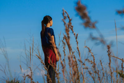 Side view of woman standing on field against sky