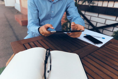 Midsection of man using mobile phone while sitting on table