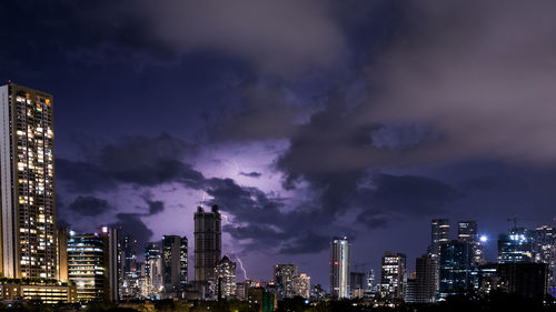 Illuminated buildings in city against sky at night