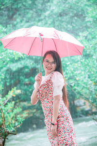 Full length of a smiling woman standing in rain