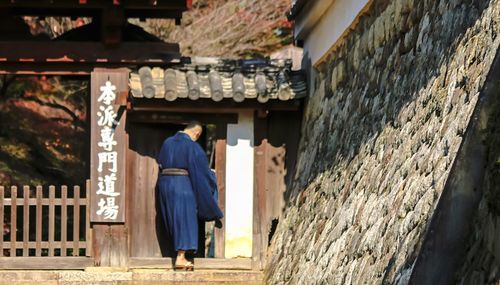 Rear view of monk entering in house