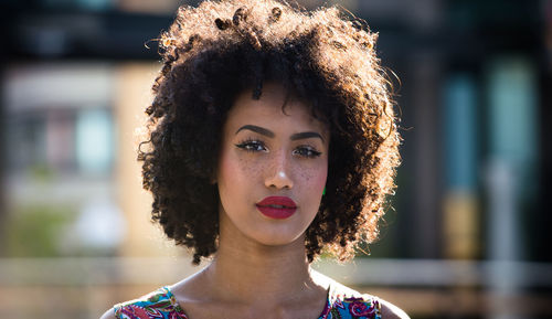 Portrait of fashionable young woman with curly hair in city