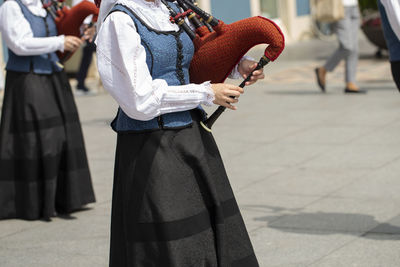 Midsection of musician playing bagpipe on street in city