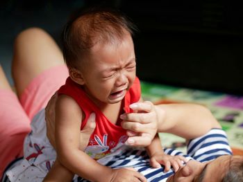 Mother carrying crying daughter at home