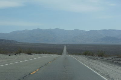 Road by mountains against sky