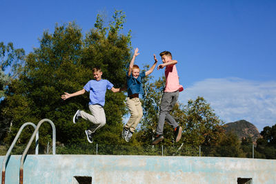 Three brothers looking joyful while in midair after jumping