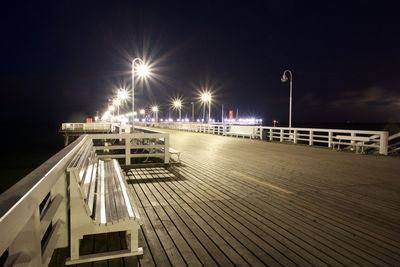 Illuminated footbridge against sky at night