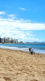 Man riding bicycle on beach against sky