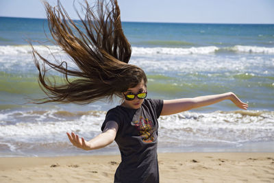Portrait of girl with tousled hair gesturing at beach