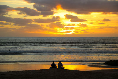Silhouette couple on shore at beach during sunset