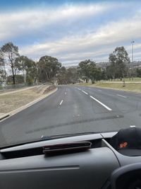 Cars on road against sky seen through car windshield