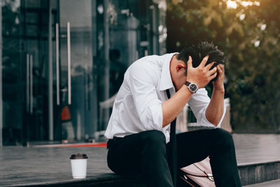 Stressed businessman with head in hands sitting on steps