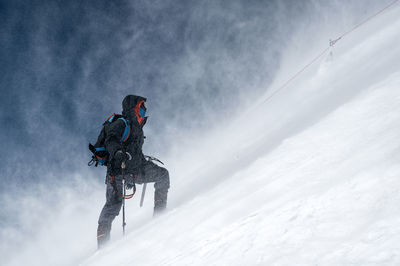 Male hiker climbing snow covered mountain on vacation