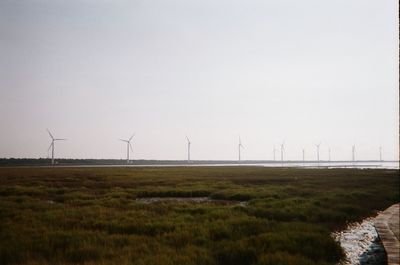 Wind turbines on field against sky