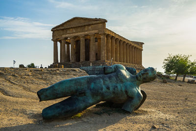 Statue on ground against monument against sky