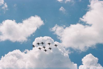 Low angle view of silhouette airplanes against sky during airshow