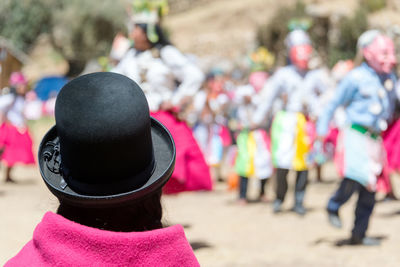 Rear view of woman looking at performers performing traditional dance during festival