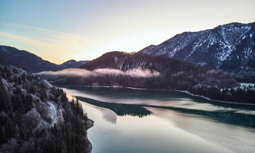 Scenic view of lake by mountains against sky during winter