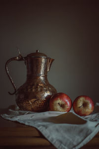 Close-up of apples and jug on table