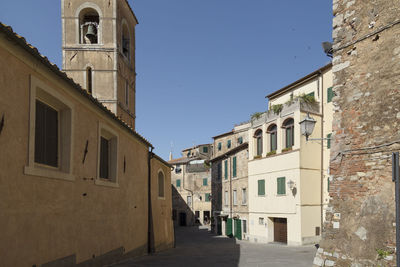 Street amidst buildings in town against clear blue sky