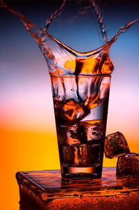 Close-up of beer in glass against sky during sunset