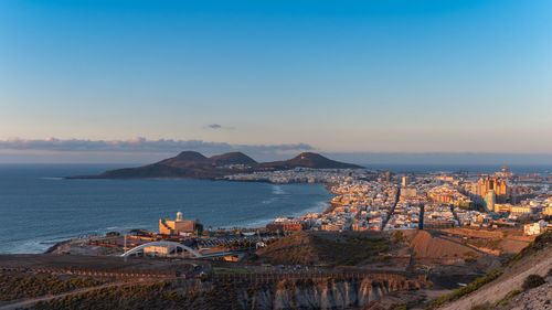 High angle view of buildings by sea against sky during sunset