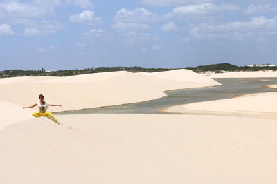 Young woman playing with sand between dunes of lencois maranhenses national park, brazil