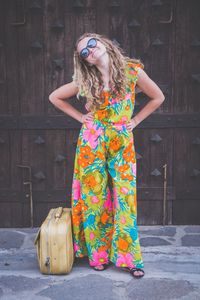 Portrait of smiling young woman standing against multi colored wall