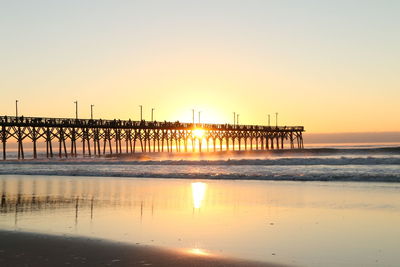 Pier over sea against clear sky during sunset