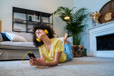 Young woman using mobile phone while sitting on bed at home