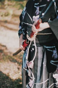 Midsection of man holding umbrella while standing on field