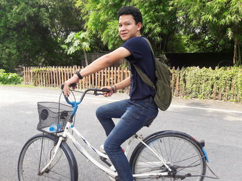 Portrait of young man riding bicycle on road