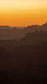 Scenic view of silhouette mountains against orange sky