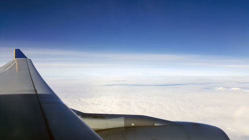 Airplane flying over clouds against blue sky