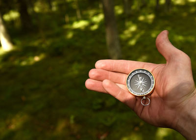 Close-up of hand holding clock against blurred background