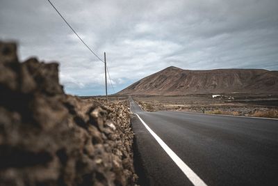 Road leading towards mountain against sky