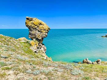 Rock formations in sea against clear blue sky