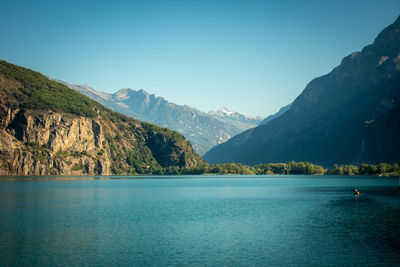 Scenic view of lake and mountains against clear blue sky