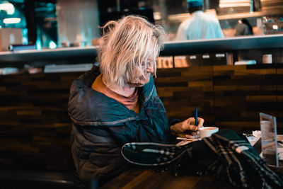 Woman holding umbrella while sitting on table