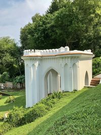 Built structure on field by trees against sky