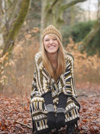 Portrait of smiling young woman standing in forest during autumn