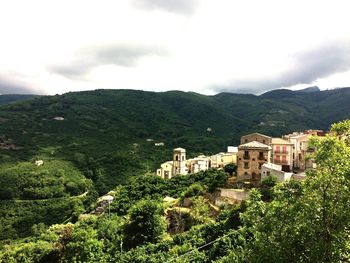 Houses on mountain against cloudy sky