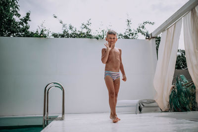 Full length portrait of shirtless man standing in swimming pool