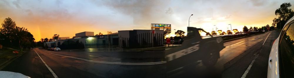Panoramic view of city street against sky during sunset