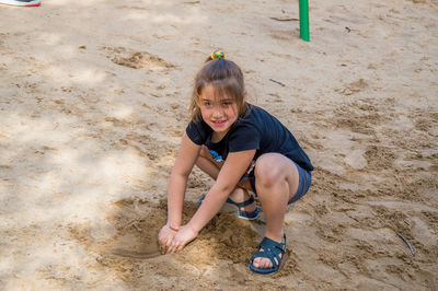 Portrait of smiling girl playing on sandy beach