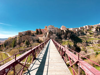 Footbridge over mountain against blue sky