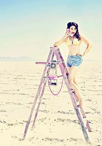 Portrait of young woman on beach against sky